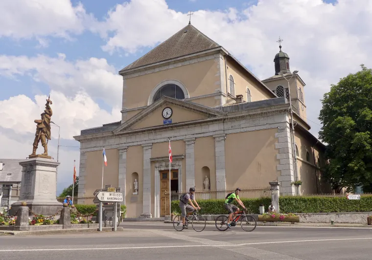 Radfahrer vor der Kirche Saint-Jean-Baptiste in Taninges